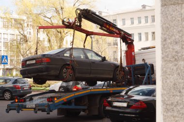 Minsk, Belarus -  April 22, 2018: Police tow truck removing an illegally parked car from the city street clipart