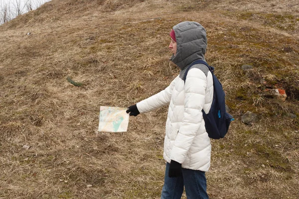 Adult young woman in warm sacual clothes travelling and looking for a route on the map how to get somewhere on the background of National Park