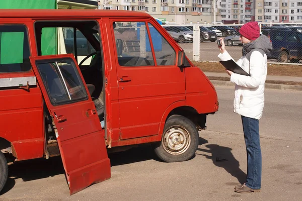 Bir başvuru formu üzerinde zarar hesaplamak için harap araba fotoğrafını genç kadın araba sigorta acentesi