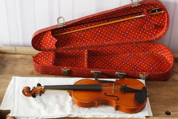 テーブルの上に弓が付いている赤いケースが付いている古いみすぼらしい黄色のバイオリン — ストック写真