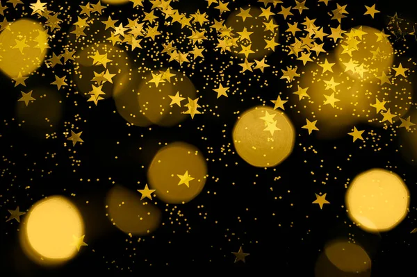 gold glitter, star confetti and bokeh lights on a black background