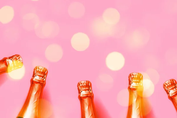 Bottiglie di champagne su sfondo rosa con luci bokeh — Foto Stock