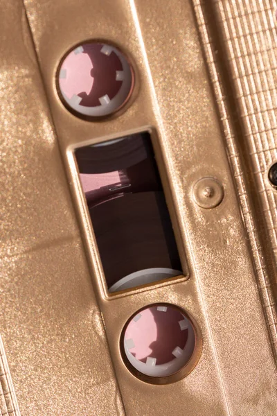 Fita cassete de ouro em um fundo rosa com sombra — Fotografia de Stock