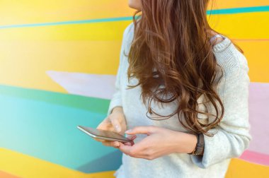 Renkli sokak duvara bir akıllı telefon kullanan açık hipster kadın