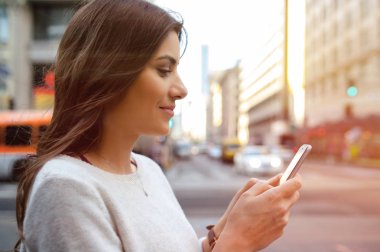 Güzel ve genç birbayan Bulvarı kentsel sahne, şehir merkezinde, günbatımında smartphone holding