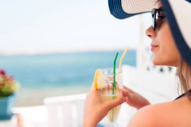 Yunanistan deniz manzaralı bir barda bir limonata içmeye güneşli bir gün plajda, genç kadının.