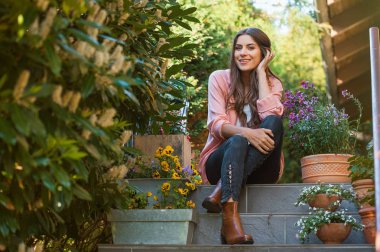 Gülümseyen ve kamera, ev terasta oturan bakarak rahat genç erkek. Hobi ve istirahat eğlence kavramı.