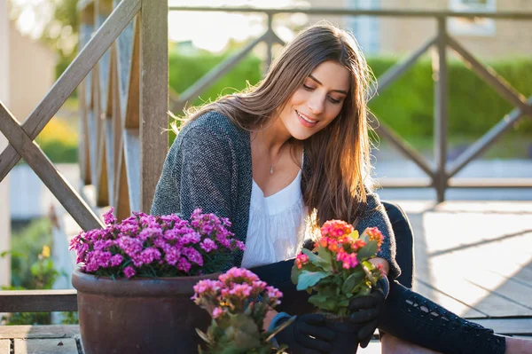 Beautiful young girl enjoy gardening on the terrace,at home, holding flowerpot. Gardening as hobby and leisure concept.
