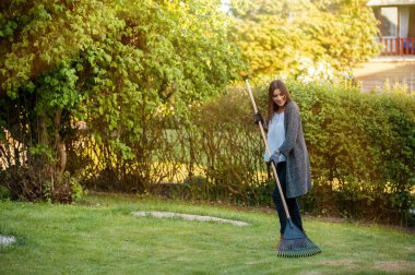 Çiçek, bitki ve bitki örtüsü ile ev arka bahçe yaprak komisyon ile gülümseyen genç kadın. Bahçe hobi ve boş zaman kavram olarak.