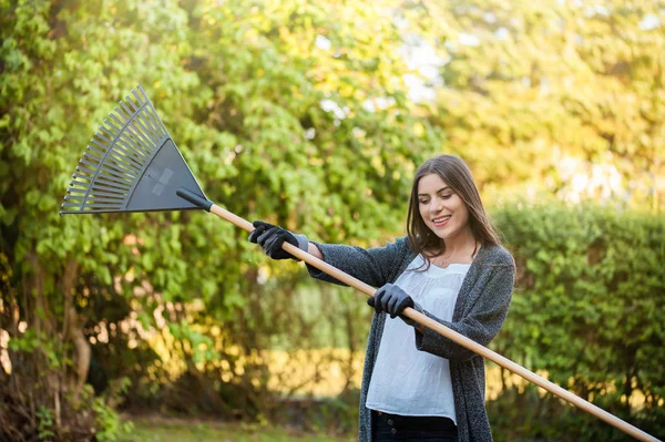 Lächelnde Junge Frau Mit Gartenlaubrechen Ihrem Heimischen Garten Mit Blumen — Stockfoto