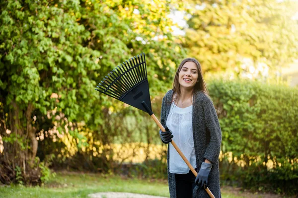 Усміхнена Молода Жінка Садовим Листям Граблів Своєму Домашньому Дворі Квітами — стокове фото
