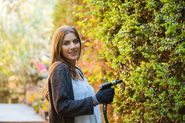 植生と彼女の家の裏庭に水をまく庭のホースで若い女性を笑顔します 趣味やレジャーの概念としての園芸 — ストック写真