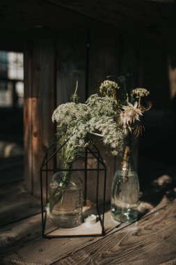 Güzel bir gün batımı karanlık ışık ahşap arka plan üzerinde bottels düzeninde güzel kır çiçekleri.