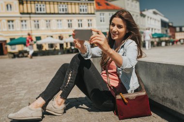 Şehir merkezinde oturan genç güzel kadın telefon ile bir Self portre alarak.