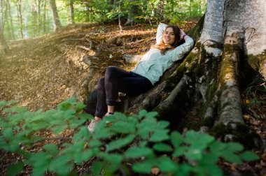 Genç kadın sonbaharda gün batımı ışığında ormanda bir sırt çantası taşıyan, ormanda bir yürüyüş.