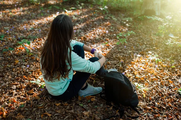 Młoda Kobieta Odpoczywa Siedząc Spacerze Lesie Plecakiem Świetle Słońca Jesiennym — Zdjęcie stockowe