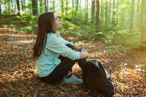 Młoda Kobieta Odpoczywa Siedząc Spacerze Lesie Plecakiem Świetle Słońca Jesiennym — Zdjęcie stockowe