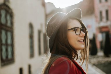 Gözlüklü genç hippi kadın şapka takıyor, eski şehrin Avrupa 'sına bakıyor.