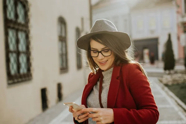 Giovane Hipster Donna Con Occhiali Che Tiene Uno Smartphone Indossa — Foto Stock