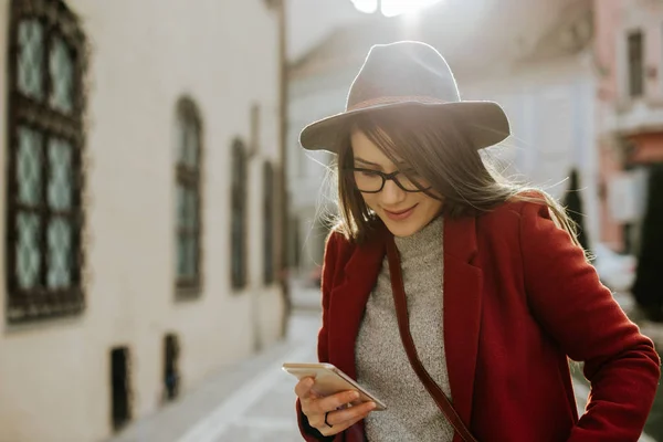 Jovem Hipster Mulher Com Óculos Segurando Smartphone Usando Chapéu Cidade — Fotografia de Stock