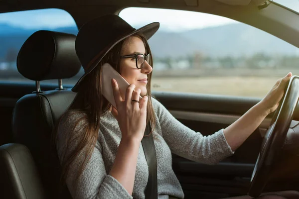 Jovem Hipster Mulher Com Óculos Chapéu Dirigindo Carro Segurando Smartphone — Fotografia de Stock