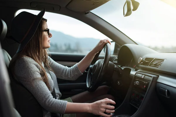車を運転する眼鏡と帽子を持つ若いヒップスターの女性 ストックフォト