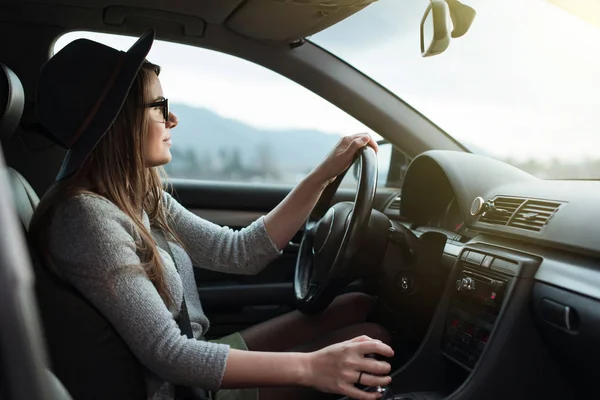 Ung Hipsterkvinna Med Glasögon Och Mössa Som Kör Bilen Stockbild