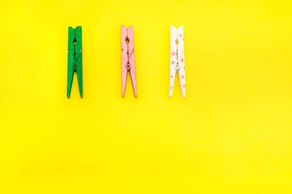 sarı arka planda üç renkli ahşap clothespin