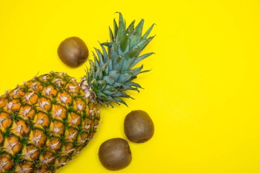 Ananas ve üç kivi parlak sarı arka planda izole