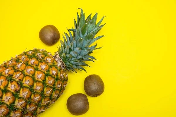 Ananas ve üç kivi parlak sarı arka planda izole