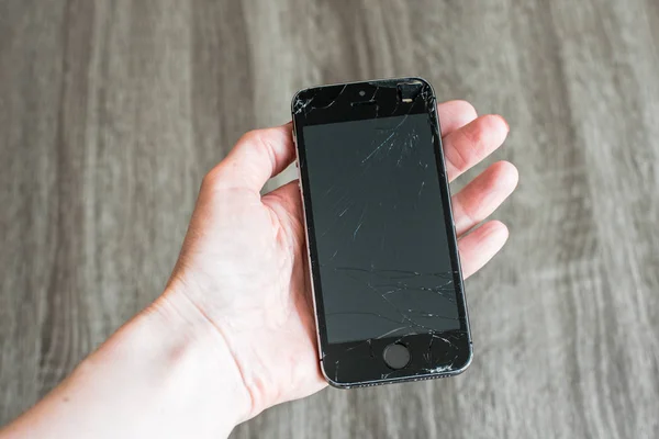 Gri arka planda elde kırık siyah telefon ekranı