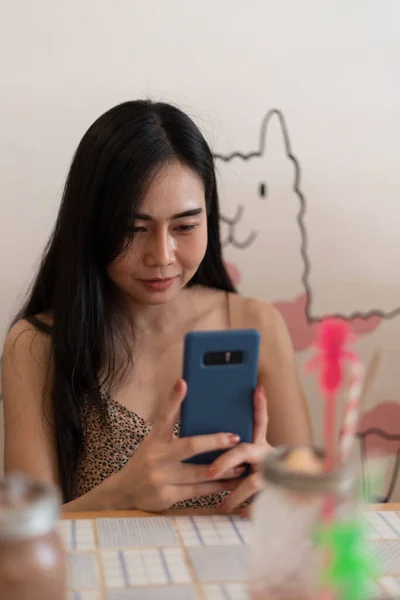 Genç bir kız kafeteryada telefonla fotoğraf çekiyor..