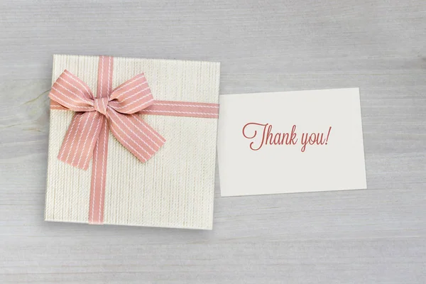 Beige gift box with pink ribbon on wood background with Thank you card, present for Thanks giving or Christmas, top view