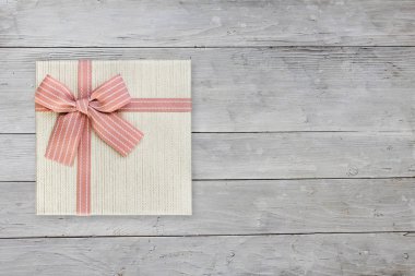Beyaz ahşap arka plan üzerinde pembe kurdele ile Hediye kutusu, kopya alanı ile üst görünümü