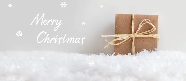 雪の結晶とメリークリスマスヘッダー グレーの背景にラフィアリボンと茶色のギフトボックス 前の雪 ストック写真