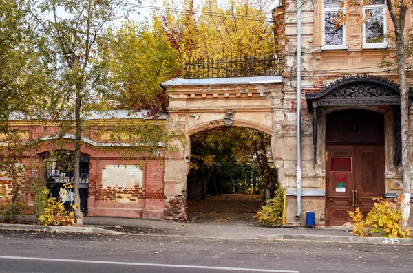 View of an arch of an entrance to a court yard of the ancient brick house in the autumn afternoon. City landscape. Architecture. Russia. Astrakhan. Outdoors. Horizontal format. Color. Photo.