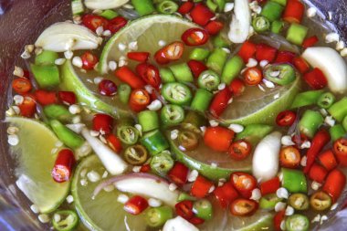 Küçük parçalara ayrılmış taze biberler, her gün Tayland yemeğine tat katmak için balık sosu, limon ve sarımsak ile tatlandırılmış şeffaf bir kaba konur..
