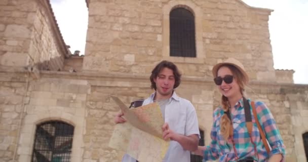 Jóvenes turistas pareja con mapa visitando una ciudad antigua — Vídeo de stock