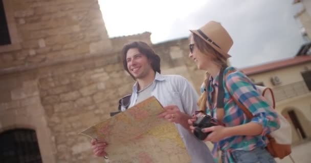 Jóvenes turistas con mapa y cámara en pintoresco pueblo — Vídeos de Stock