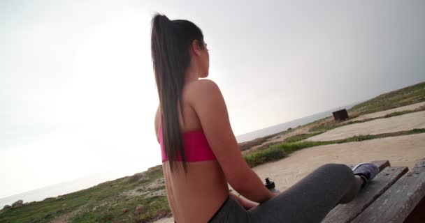 Ung vältränad kvinna dricksvatten och vila efter utomhus träning — Stockvideo