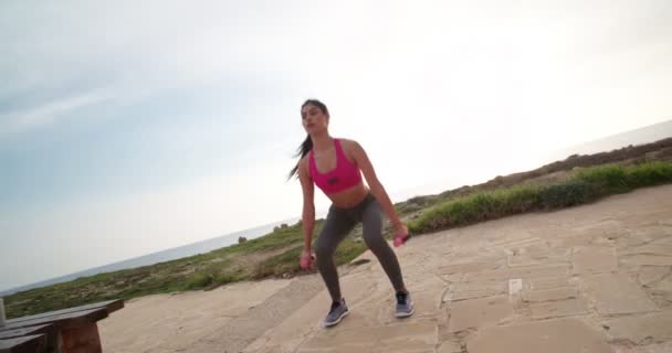 Junge athletische Frau macht Kniebeugen und Bizeps-Locken mit Hanteln — Stockvideo