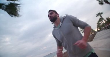 Denizin kenarında kulaklık takan zinde genç bir adam.