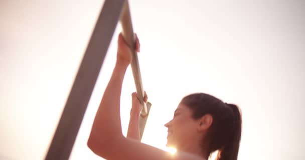 Jovem atleta feminina fazendo pull ups no bar de ginástica ao ar livre — Vídeo de Stock