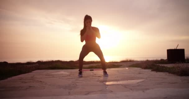 Young fit woman exercising her legs with resistance band outdoors — Stock Video