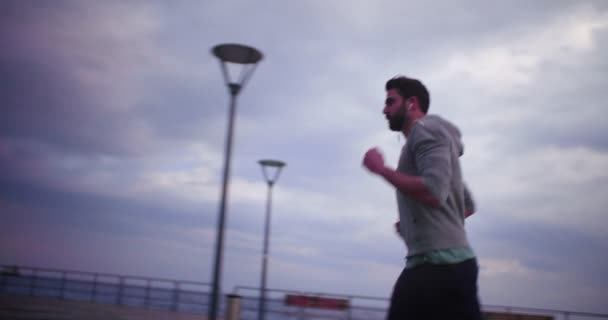 Hombre escuchando música y corriendo junto al mar — Vídeo de stock