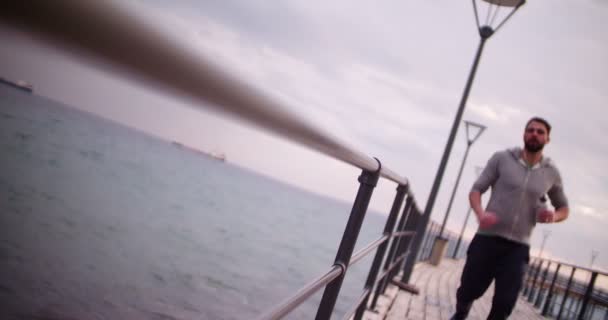 年轻的健康男子拿着水瓶在码头上奔跑 — 图库视频影像