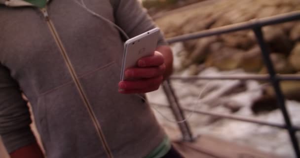 Молодий спортсмен смс на своєму смартфоні під час сеансу бігу — стокове відео