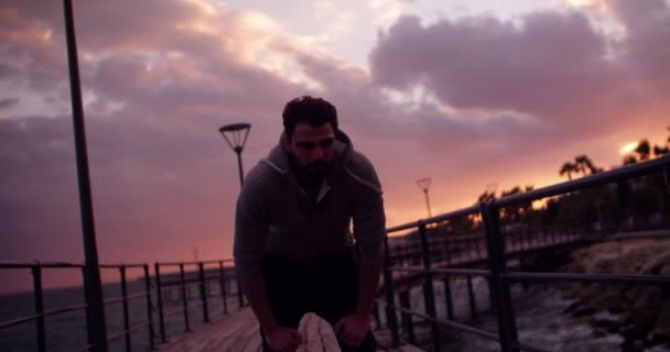 Moe van de jonge mannelijke atleet hardlopen aan zee bij zonsondergang — Stockvideo