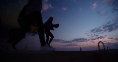 Hippi arkadaşlar ellerinde sis bombası tutuyorlar ve gün batımından sonra kaçıyorlar.