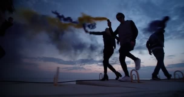 Groep van tieners vrienden rennen en feesten met multi-gekleurde rookbommen — Stockvideo